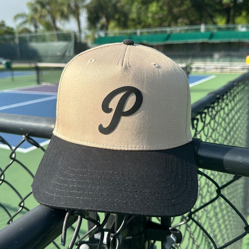Beige and black cap with a 'P' logo on a bike against a tennis court background